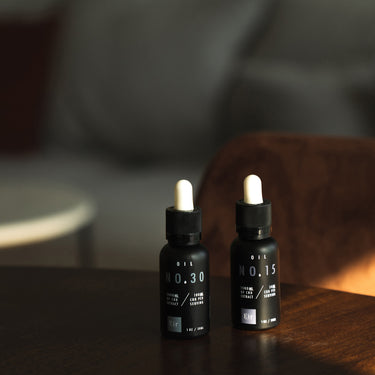Dwie butelki olejków CBD, 'No. 30' i 'No. 15', marki Eir na drewnianym stole w przytulnym wnętrzu z miękkim oświetleniem.